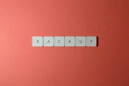 Keyboard keys spelling BACKUP on a coral surface, representing WordPress backup and restore