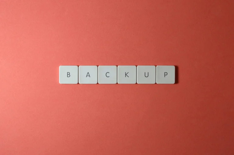 Keyboard keys spelling BACKUP on a coral surface, representing WordPress backup and restore